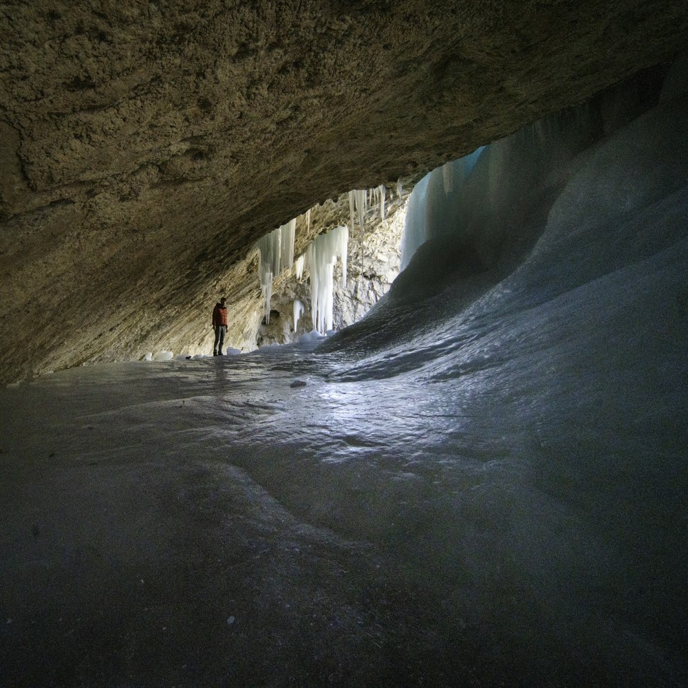 person in white shirt walking inside cave