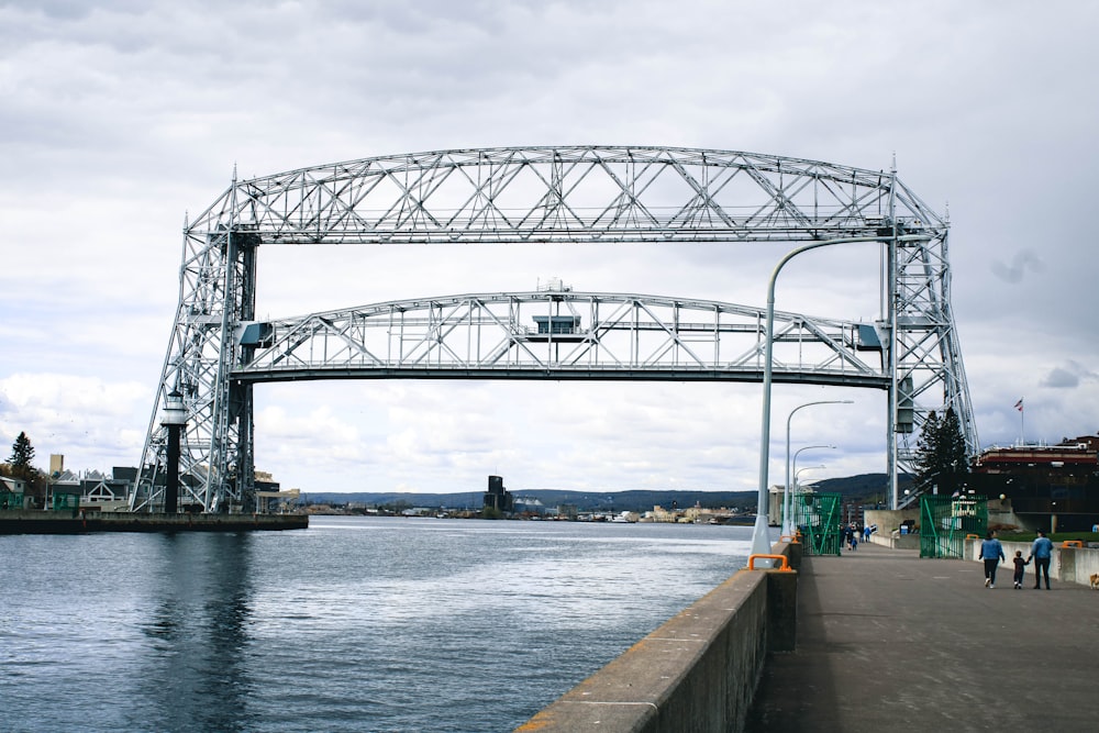 Pont en métal gris au-dessus de la rivière sous le ciel blanc pendant la journée