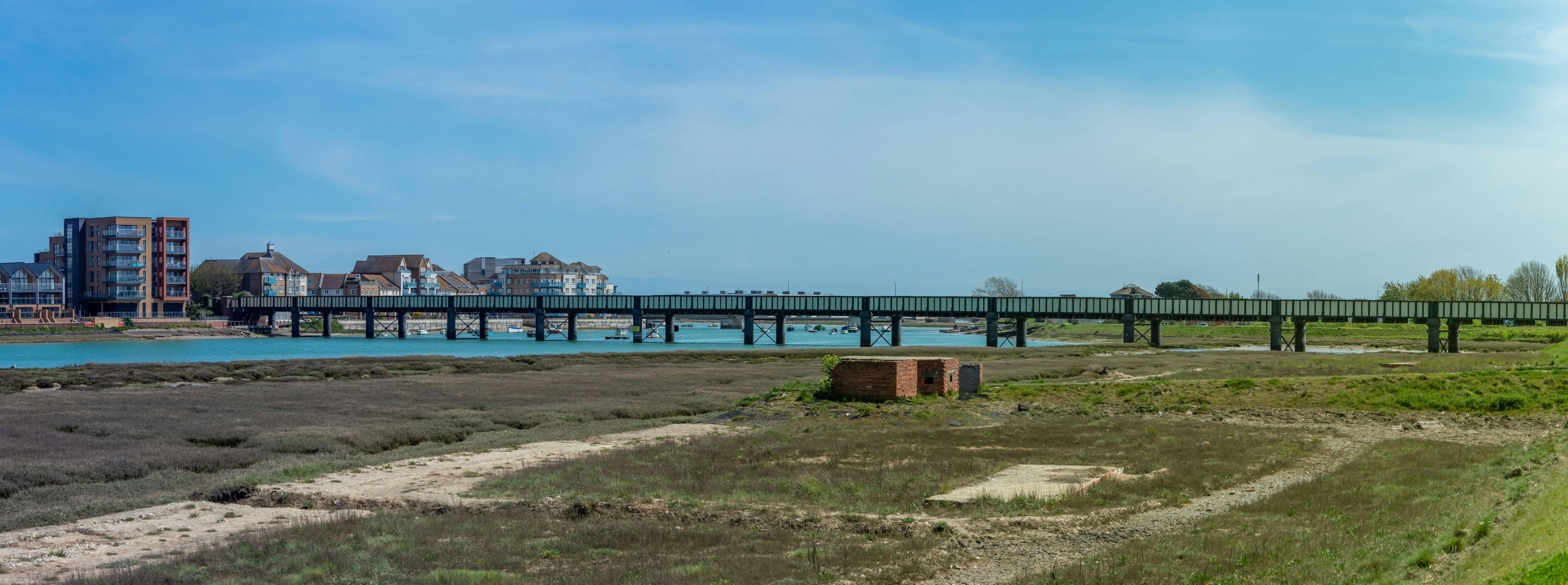 brown wooden dock on sea under blue sky during daytime, View from near to airport of Shoreham and railway bridge. Panorama