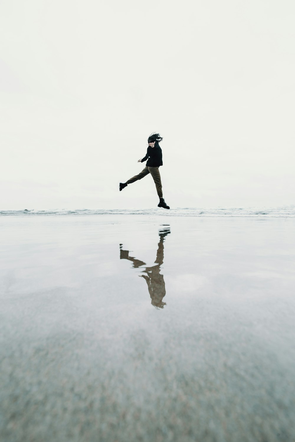 man in black shirt and black shorts standing on white sand during daytime