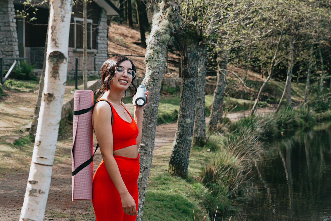 woman in red tank top standing beside tree