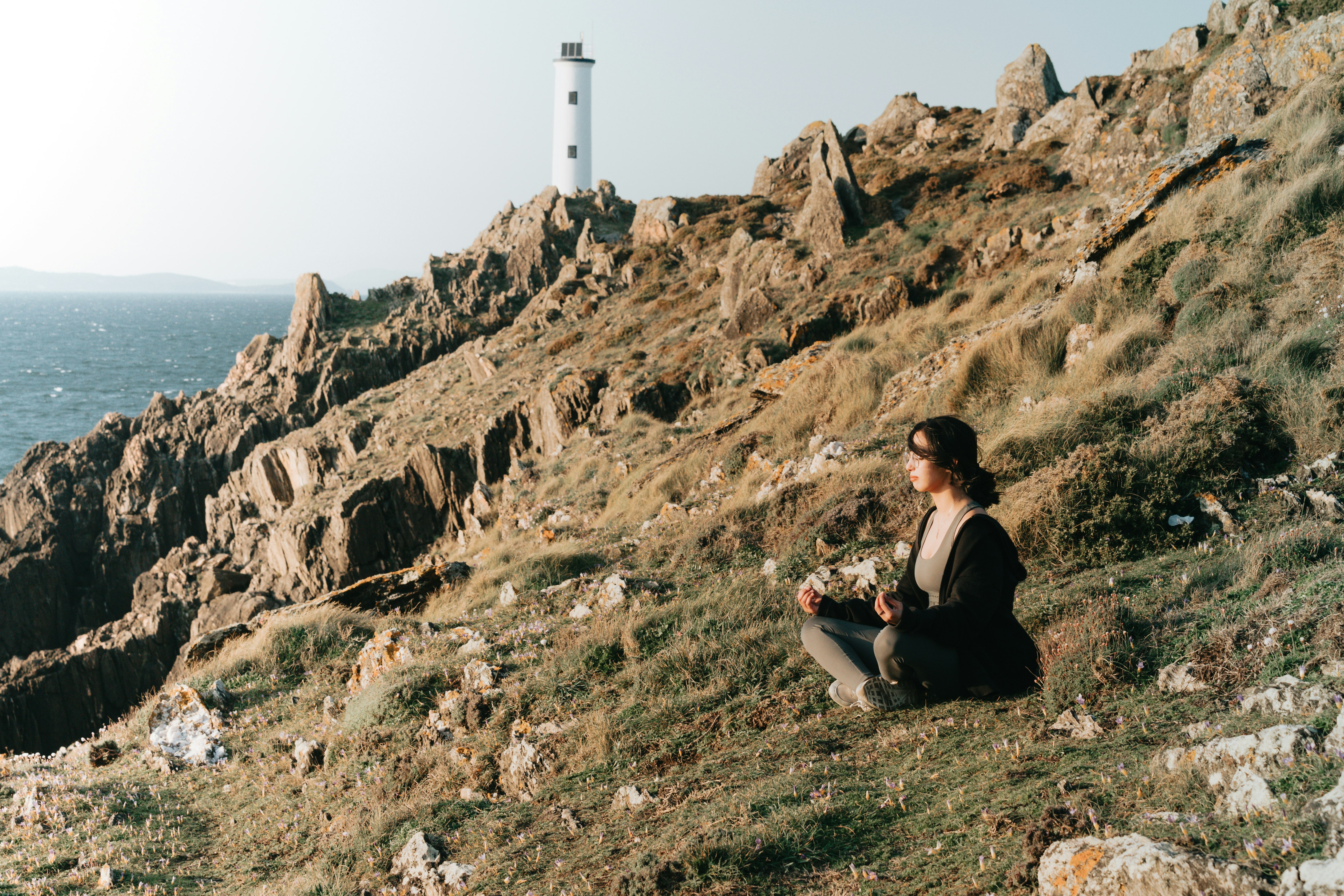 woman in black jacket sitting on brown rock mountain during daytime