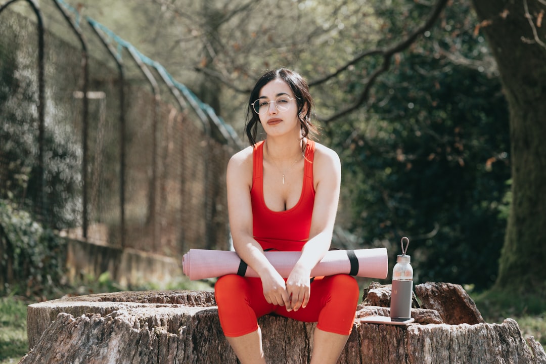 woman in white tank top and red shorts sitting on brown concrete bench