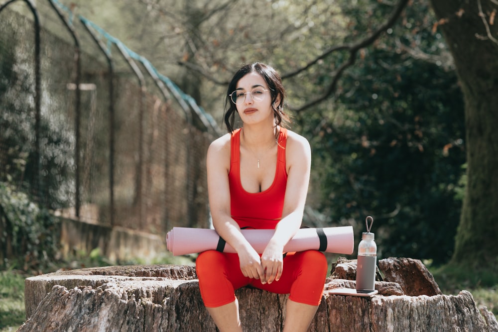 woman in white tank top and red shorts sitting on brown concrete bench