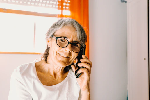 A cheerful senior woman smiling while video calling her family on a tablet in a cozy living room.