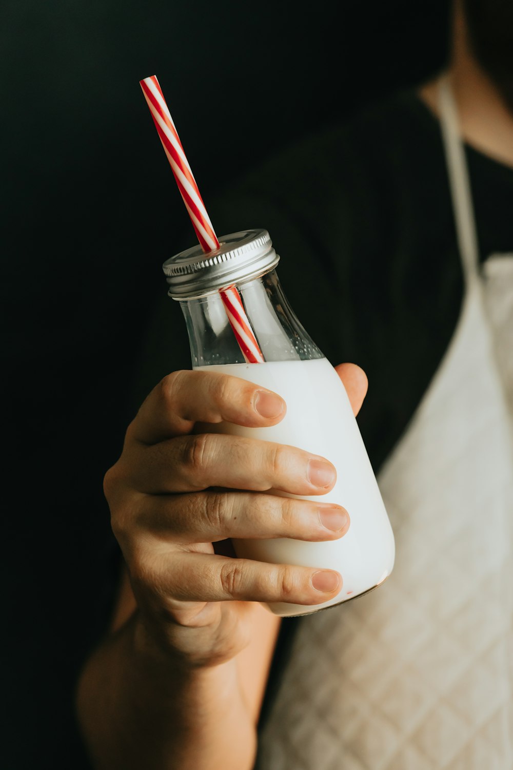 person holding clear glass jar with red straw