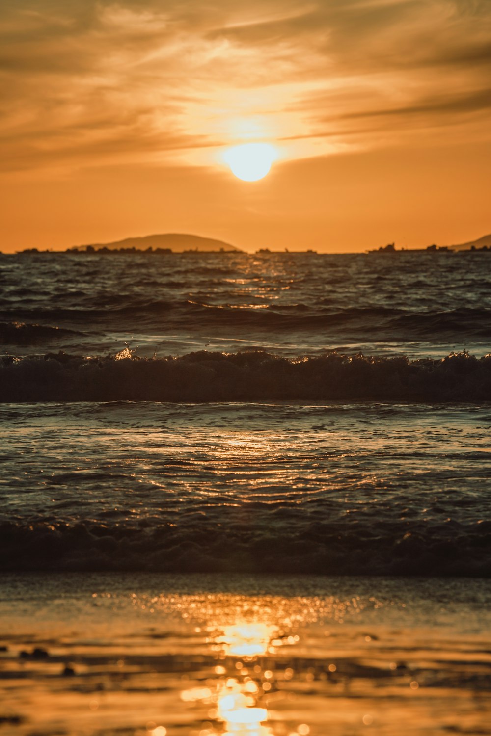 sea waves crashing on shore during sunset