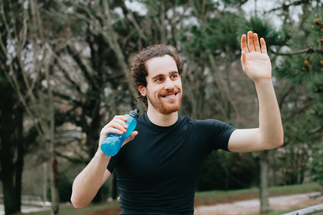 man in black crew neck t-shirt holding blue plastic bottle