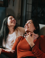 woman in red long sleeve shirt sitting beside woman in white long sleeve shirt