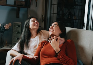 woman in red long sleeve shirt sitting beside woman in white long sleeve shirt