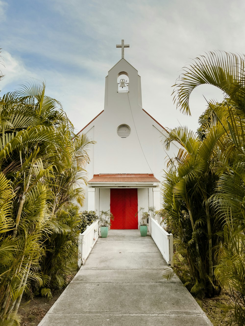 white and red concrete building near palm trees under blue sky during daytime