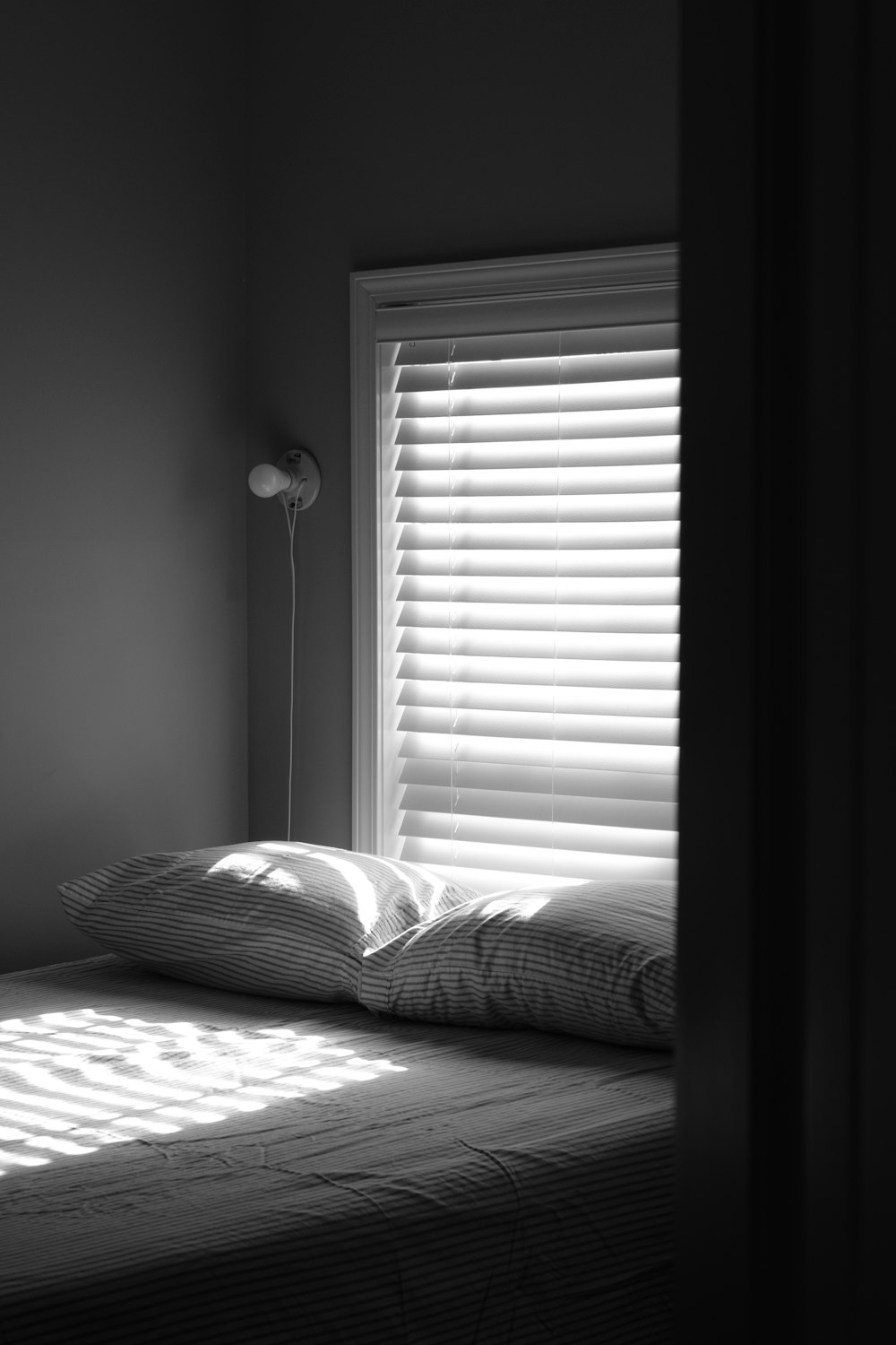 grayscale photo of bed with pillows