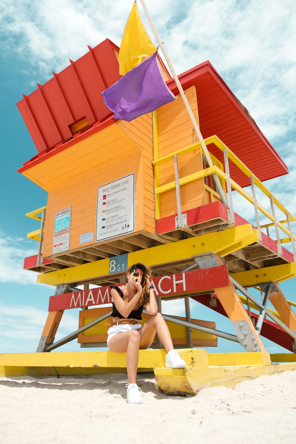 Frau im schwarzen Bikini sitzt tagsüber auf gelben Holztreppen