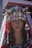 A mannequin head is adorned with a traditional and elaborate headpiece featuring metallic ornaments and conical shapes. The headpiece includes silver coins and intricate designs, with a veil that has lace detailing draped over the mannequin. The mannequin's hair is long and dark, styled in loose waves.