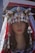 A mannequin head is adorned with a traditional and elaborate headpiece featuring metallic ornaments and conical shapes. The headpiece includes silver coins and intricate designs, with a veil that has lace detailing draped over the mannequin. The mannequin's hair is long and dark, styled in loose waves.