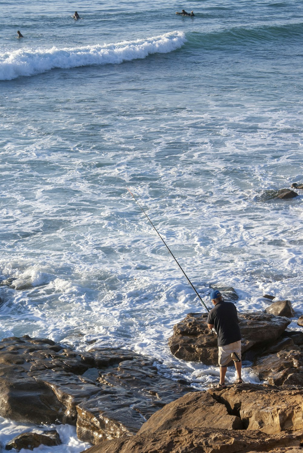 a man standing on top of a rocky beach next to the ocean