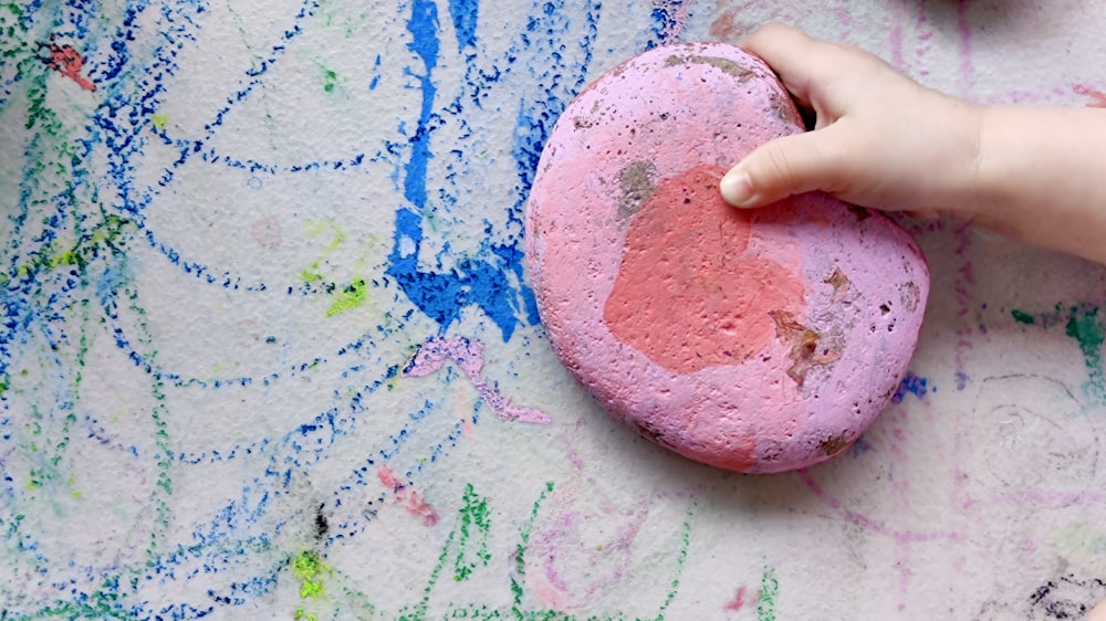 person holding pink and blue paint