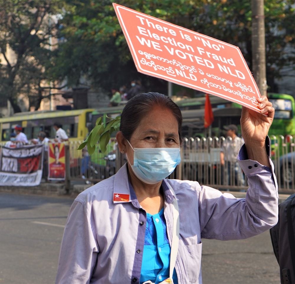 man in gray button up long sleeve shirt holding red and white signage