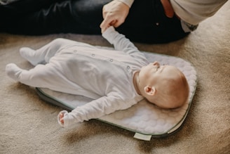 baby in white onesie lying on gray textile