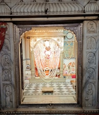 Close-up of radiant deity adorned with flowers in the temple altar.