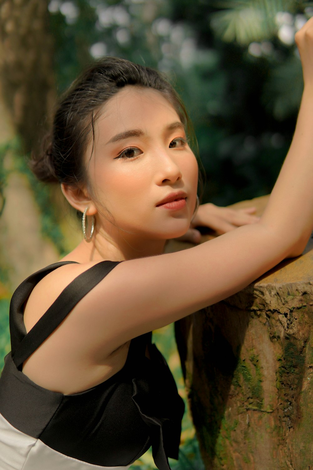 woman in black tank top leaning on brown tree trunk