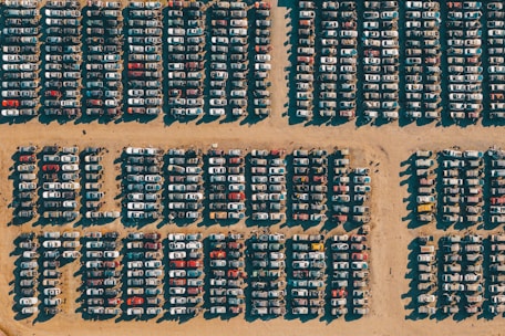 A bustling car lot filled with various used cars under bright sunlight.