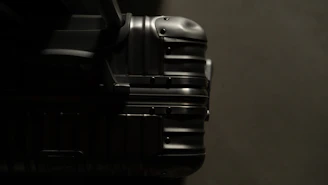 Close-up of a sleek black suitcase with gold accents, highlighting its smooth zipper and handle.