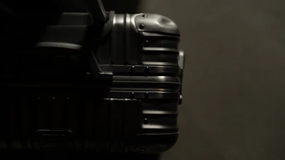 Close-up of a sleek black suitcase with gold accents, highlighting its smooth zipper and handle.