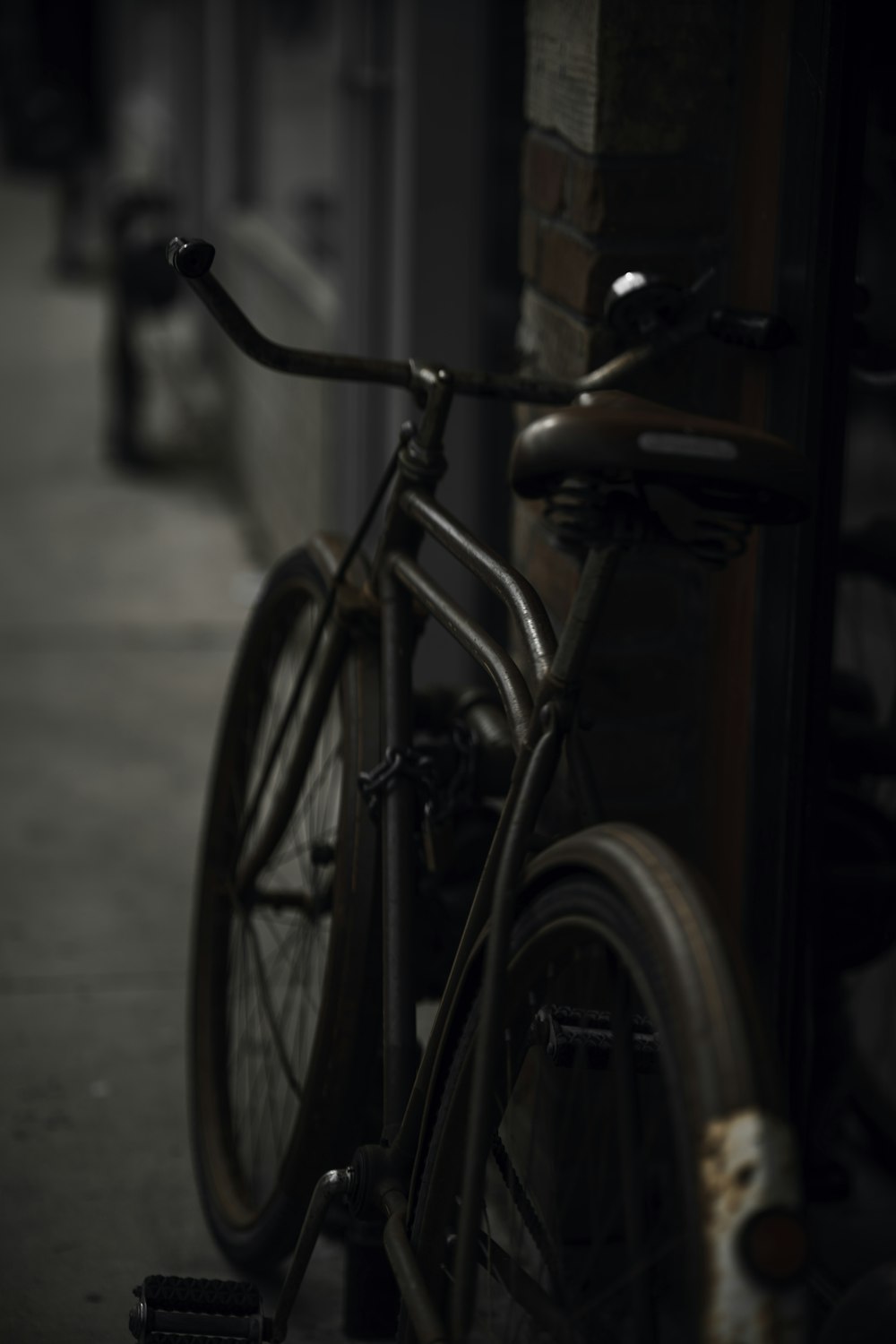 black city bike parked beside brown wooden wall