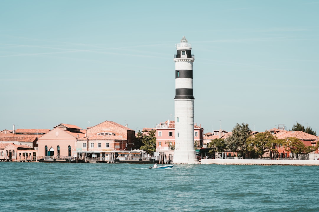 white lighthouse near houses and body of water during daytime