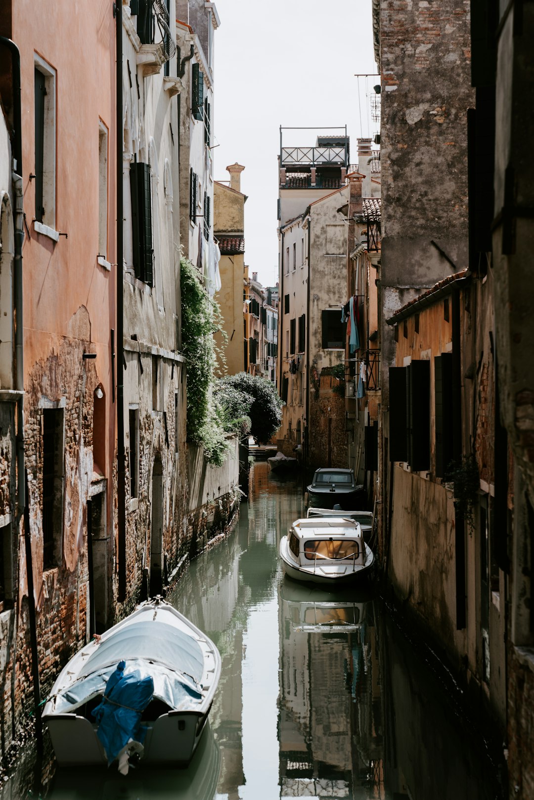 white boat on river between brown concrete buildings during daytime