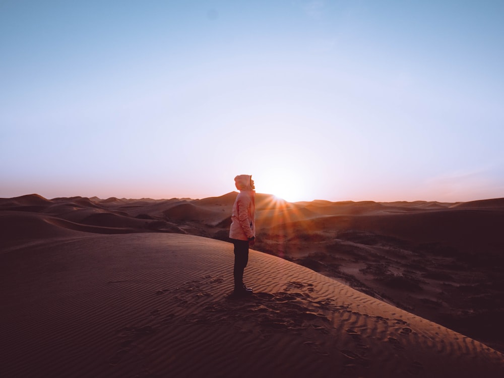 man in brown jacket standing on brown sand during daytime