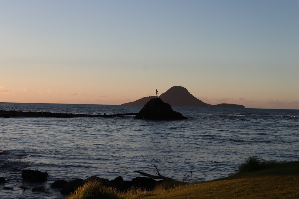 silhouette of mountain on body of water during sunset