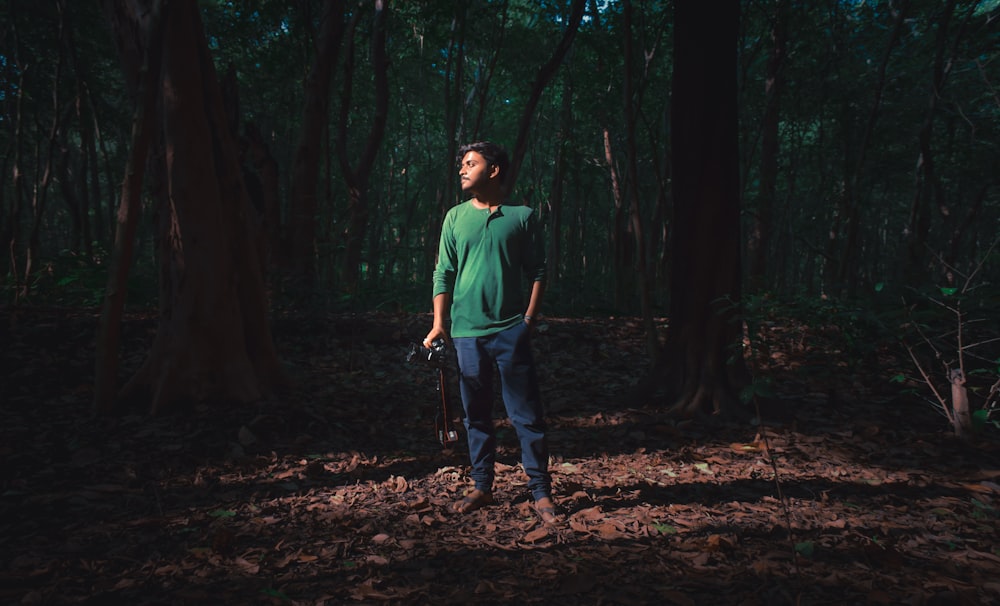 man in green crew neck t-shirt and blue denim jeans standing on brown soil