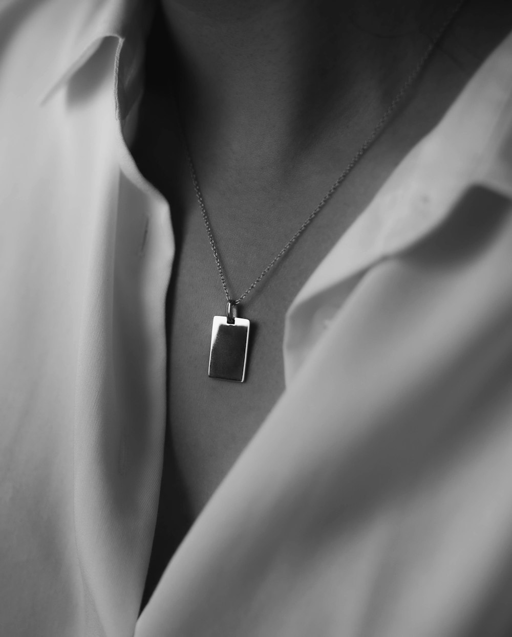 person wearing silver necklace with heart pendant