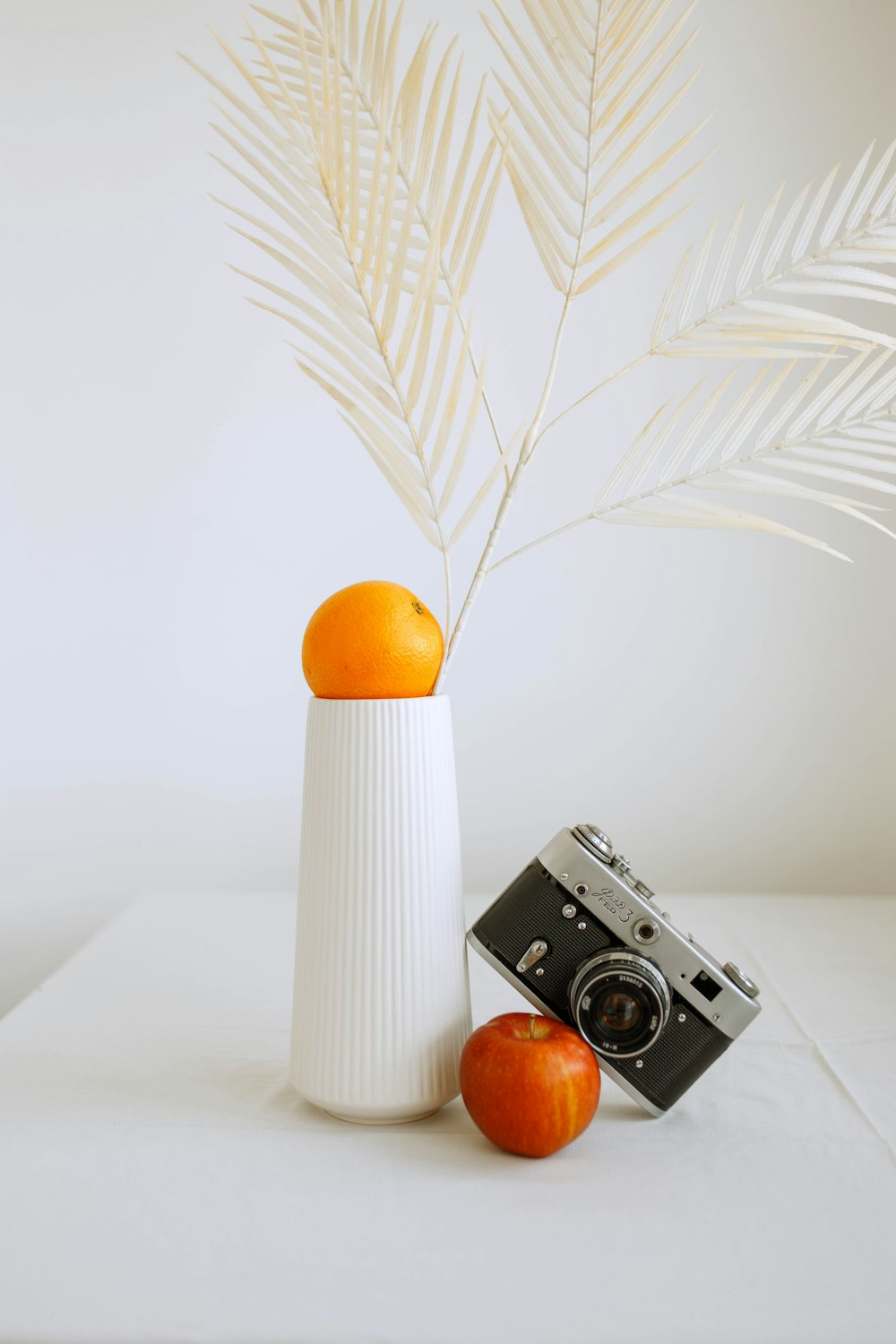 câmera branca e preta ao lado da fruta laranja