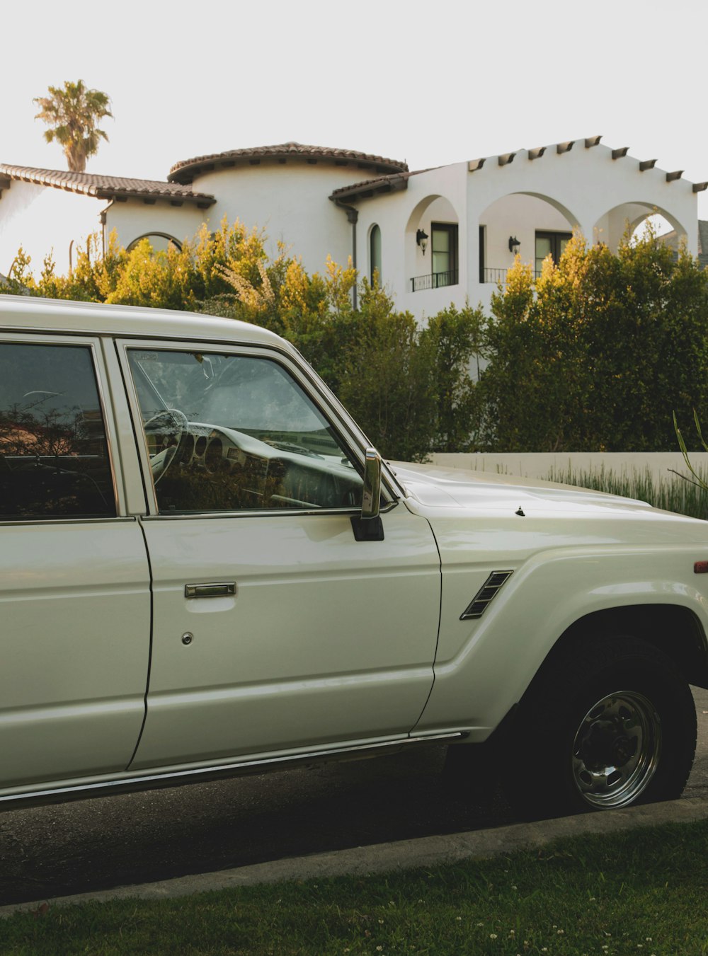 white suv parked near green trees during daytime