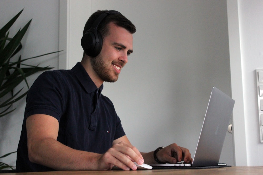 man in black polo shirt using laptop computer