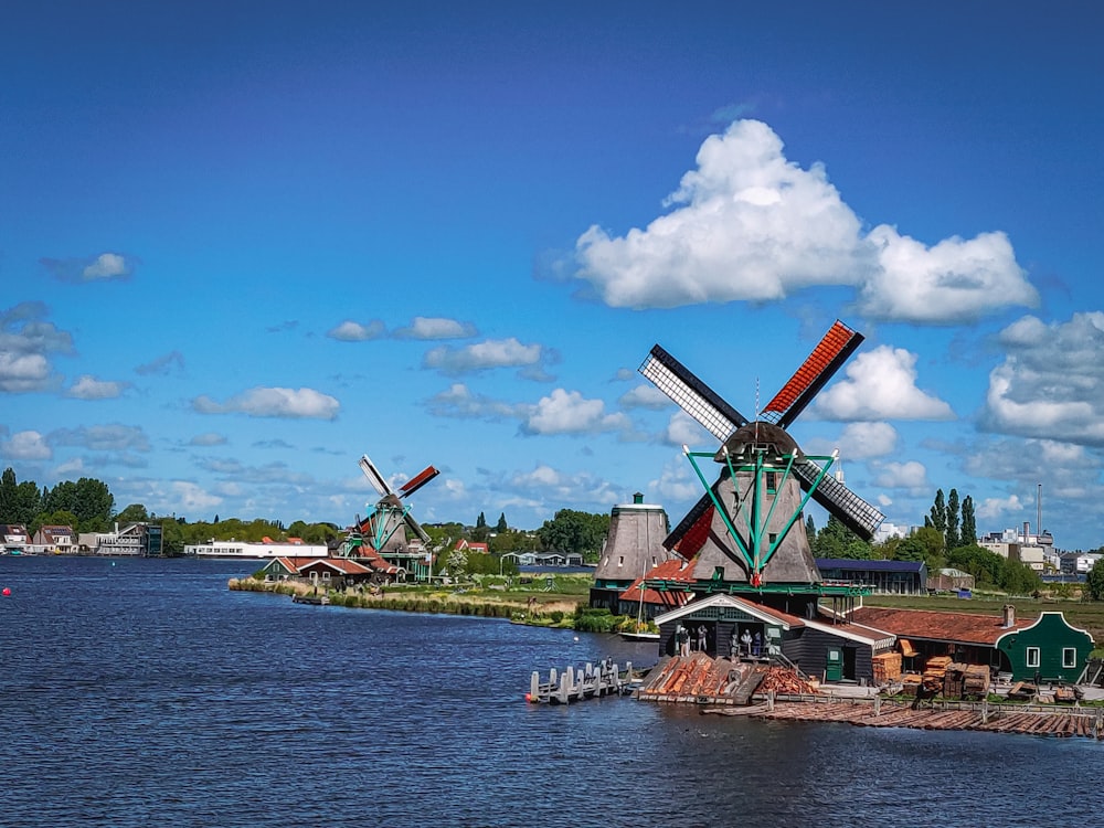 windmill near body of water under blue sky during daytime