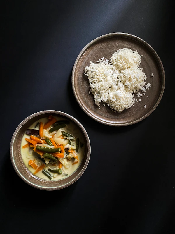 Soft rice hoppers served with a bowl of pale coconut-milk vegetable stew