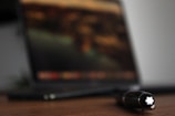 Soft-focus image of a journal and pen on a wooden desk.
