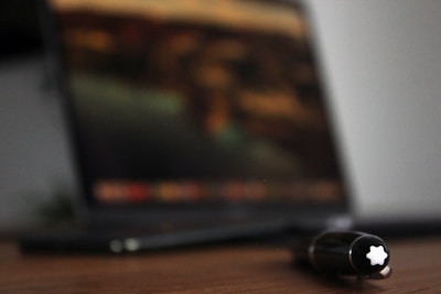 Soft-focus image of a journal and pen on a wooden desk.