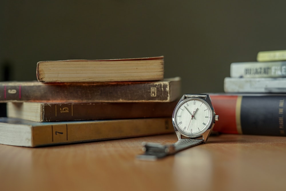 Reloj analógico redondo plateado sobre mesa de madera marrón