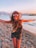 woman in black tank top and black shorts wearing black sun hat standing on beach shore