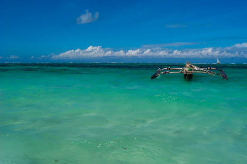 A vibrant outrigger boat gliding over crystal-clear turquoise waters near lush Caramoan islands under a bright blue sky.