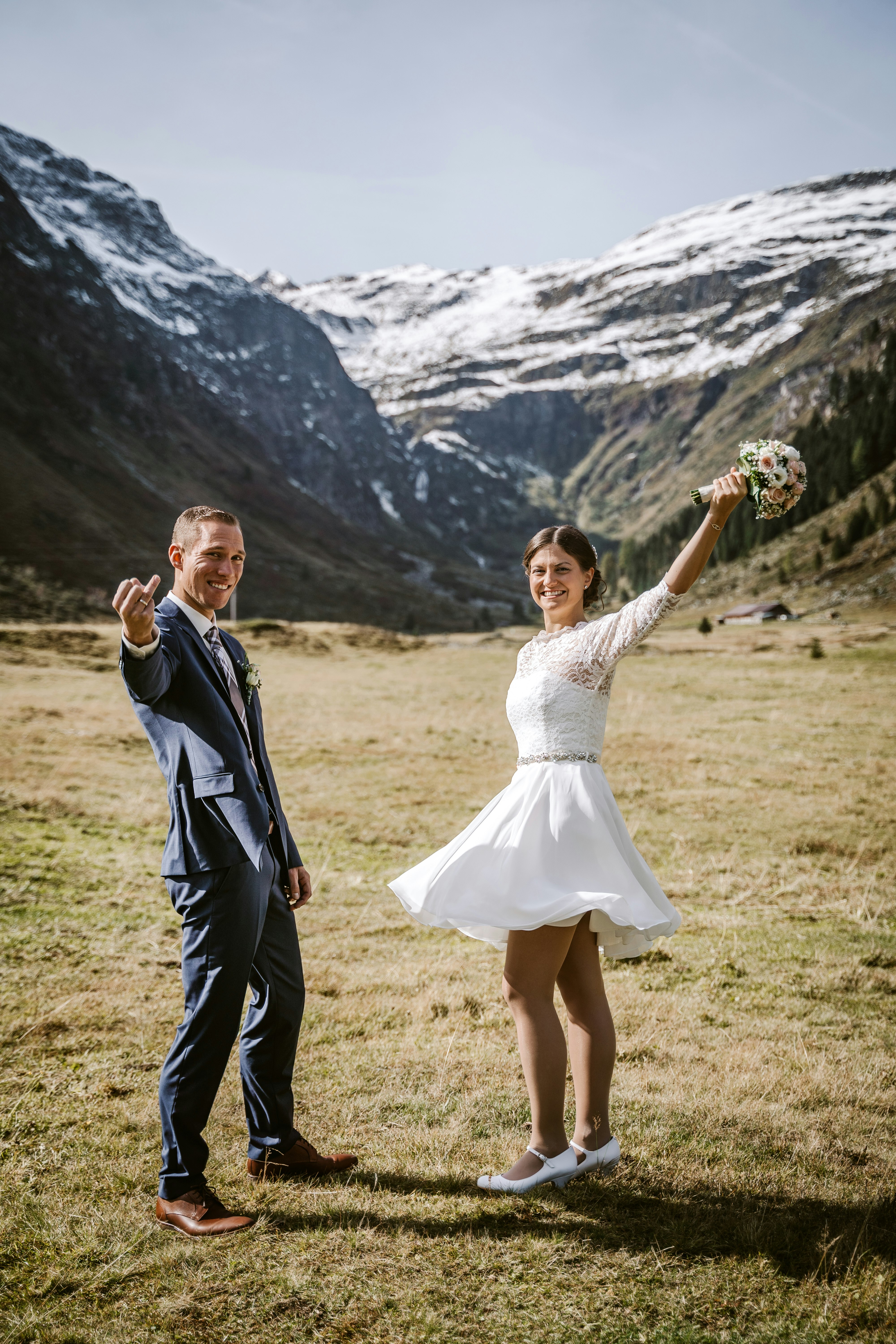 man in black suit holding woman in white dress on green grass field during daytime