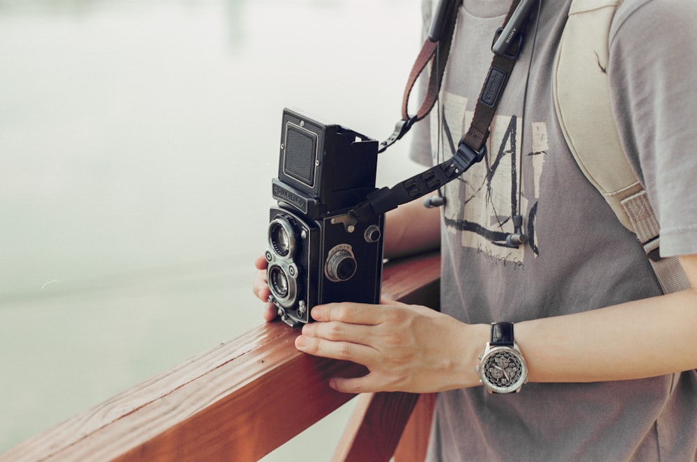 person holding black and silver camera