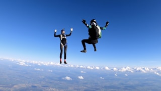 2 women in black jacket and pants jumping on white clouds during daytime