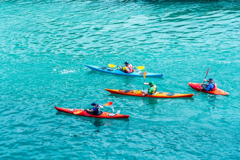 2 persone a cavallo su kayak rosso su specchio d'acqua durante il giorno