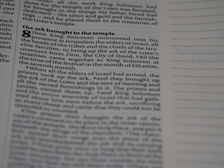 A close-up shot of a page in a book features a biblical text with visible chapter and verse numbers. The text discusses King Solomon and the ark being brought to the temple, with various small headings in bold. On the right side, there are empty lines for notes.